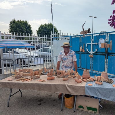 Un artisan expose ses créations sous les bougainvilliers